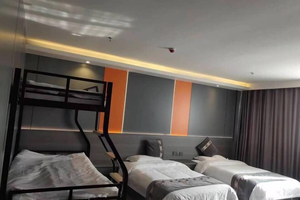 Une chambre d’hôtel avec des lits superposés, un lit plat et un décor mural moderne.
