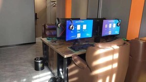 Ein moderner Arbeitsplatz mit zwei Computerbildschirmen, einer Tastatur und einem Ledersessel.