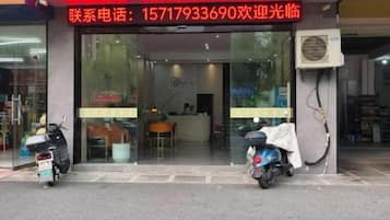 A storefront with a contact number, a reception area, and two scooters parked outside.