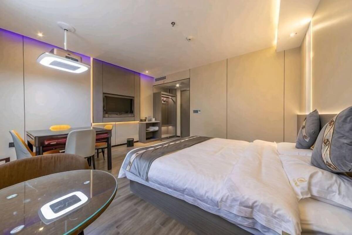 Une chambre d’hôtel moderne équipée d’un lit, d’un bureau, d’une chaise et d’un téléviseur.