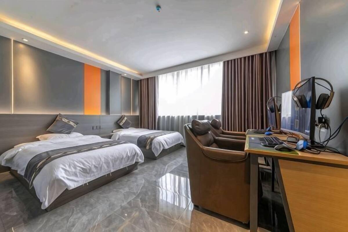 Une chambre d’hôtel avec deux lits, un bureau et une chaise.