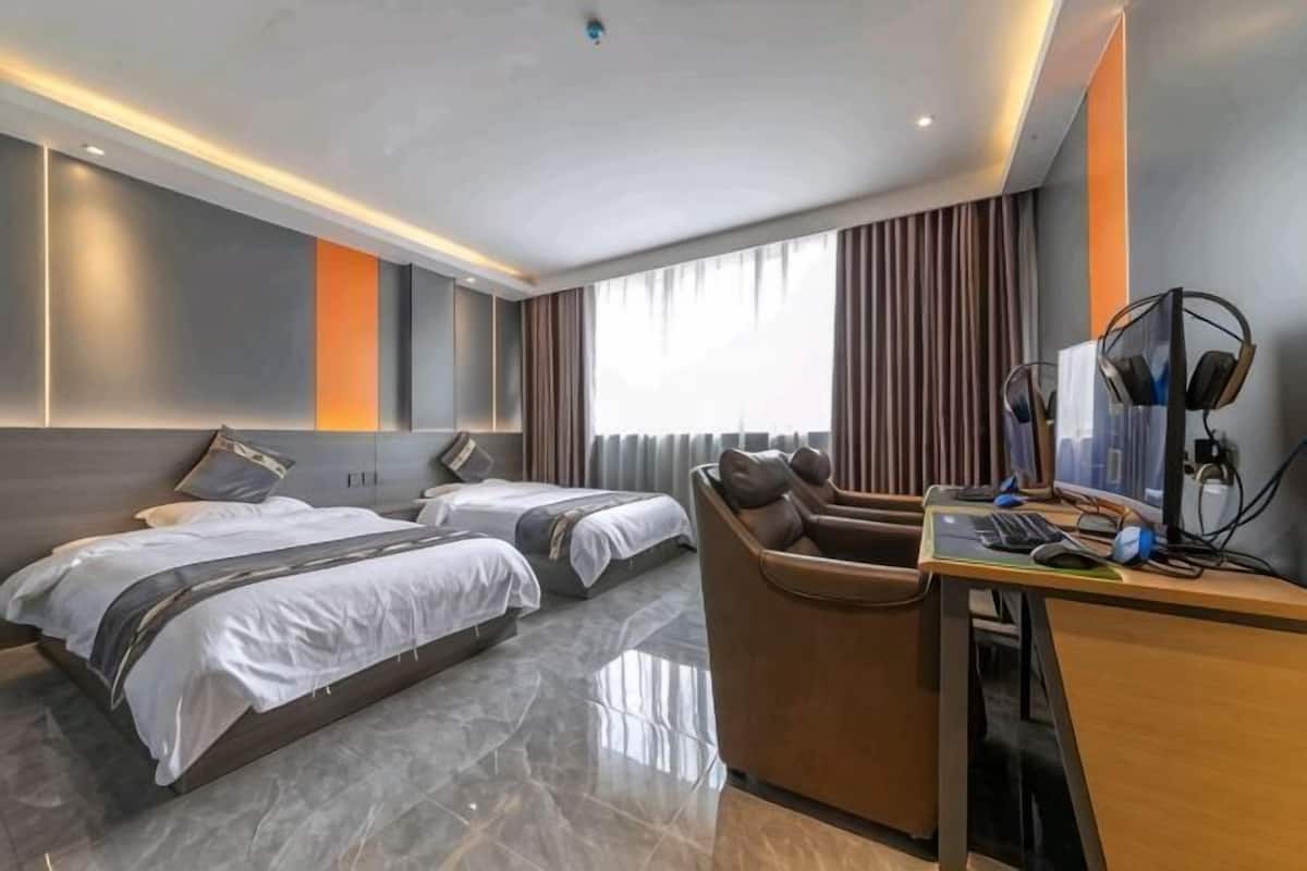 A hotel room with two beds, a desk, and a chair.