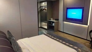 Ein modernes Hotelzimmer mit einem Bett, einem an der Wand befestigten Fernseher, einem Kleiderschrank und einem Spiegel.