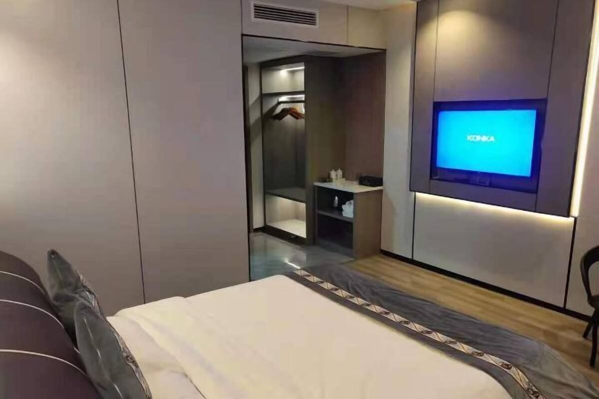 Une chambre d’hôtel moderne équipée d’un lit, d’un téléviseur fixé au mur, d’une armoire et d’un miroir.