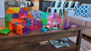 A living room with a coffee table displaying colorful geometric blocks and a magazine titled "Birds of Prey".