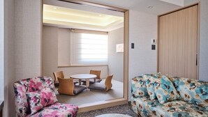 Ein modernes Hotelzimmer mit einer Couch, einem Sessel, einem kleinen Tisch und einem Spiegel.