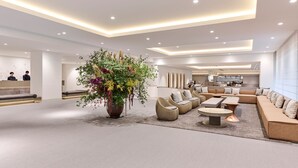 Eine geräumige Lobby mit einer großen Blumenkomposition, bequemen Sitzgelegenheiten und einer modernen Küche im Hintergrund.