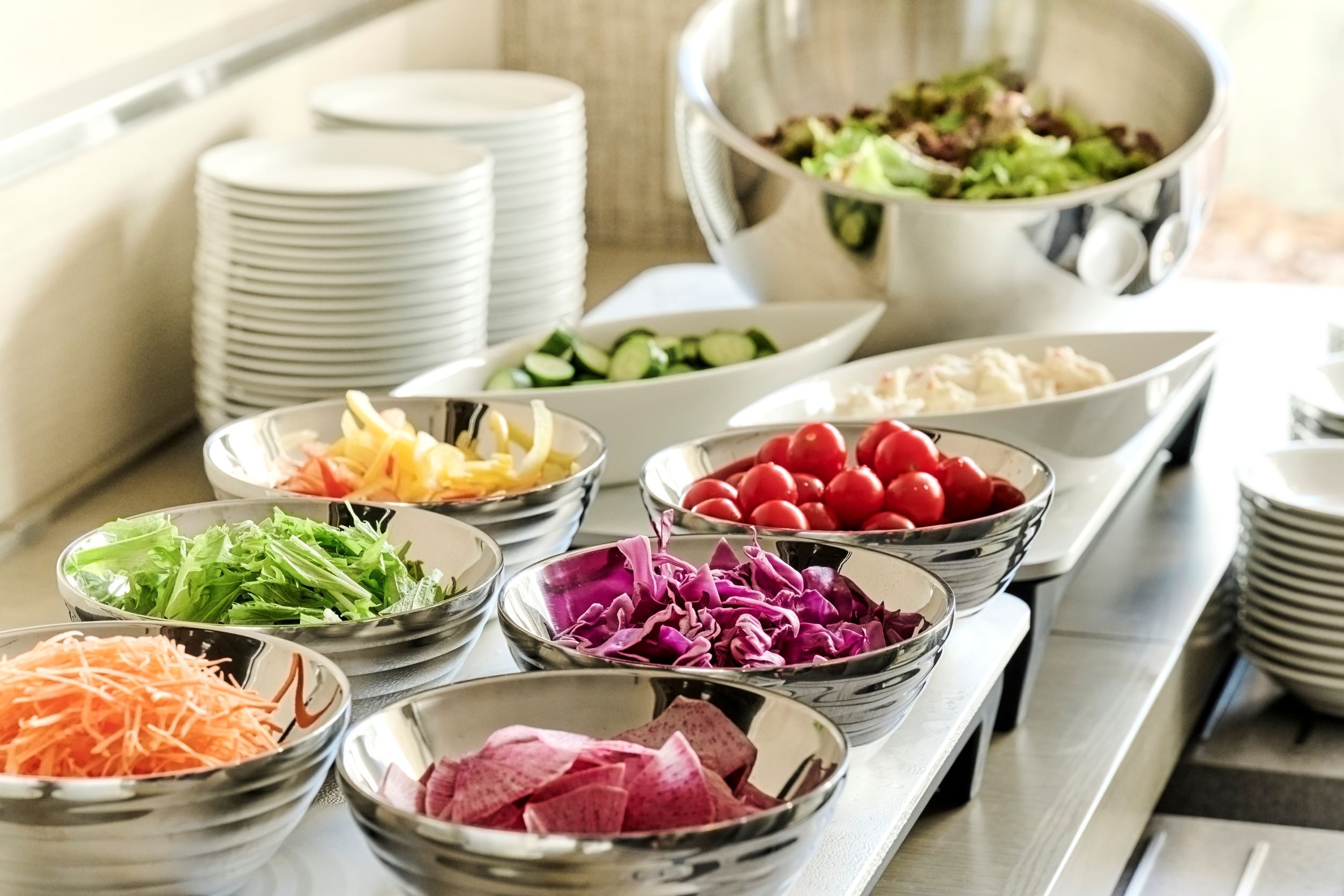 Un bufé con diversos alimentos en recipientes, como ensaladas, verduras y carnes.