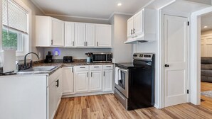 Una cocina moderna con armarios blancos, horno de acero inoxidable y microondas.