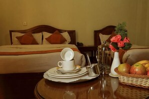 Ein Hotelzimmer mit einem Bett, einem Esstisch mit Kaffeemaschine, Tellern, einer Tasse und einer Obstschale.