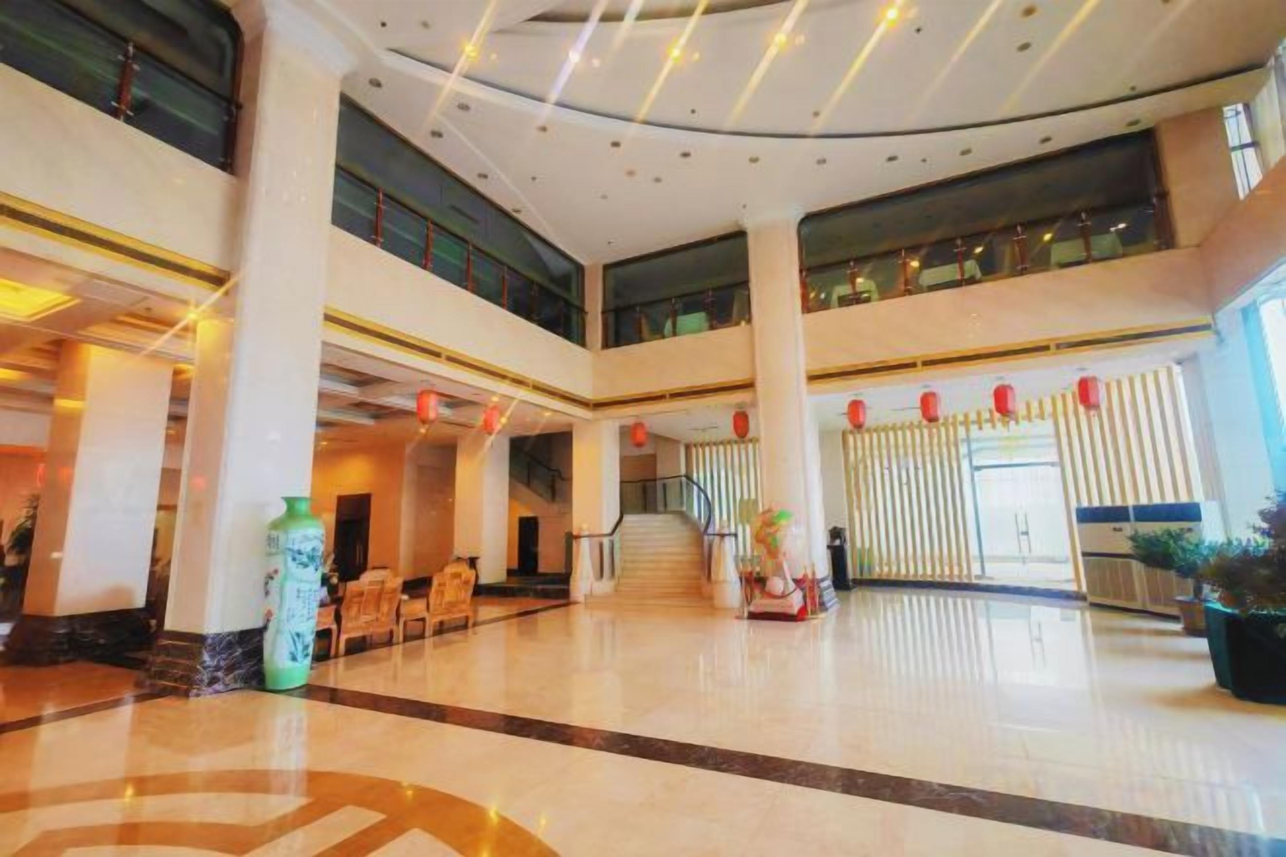 A spacious lobby with a high ceiling, multiple seating areas, and a staircase leading to an upper level.