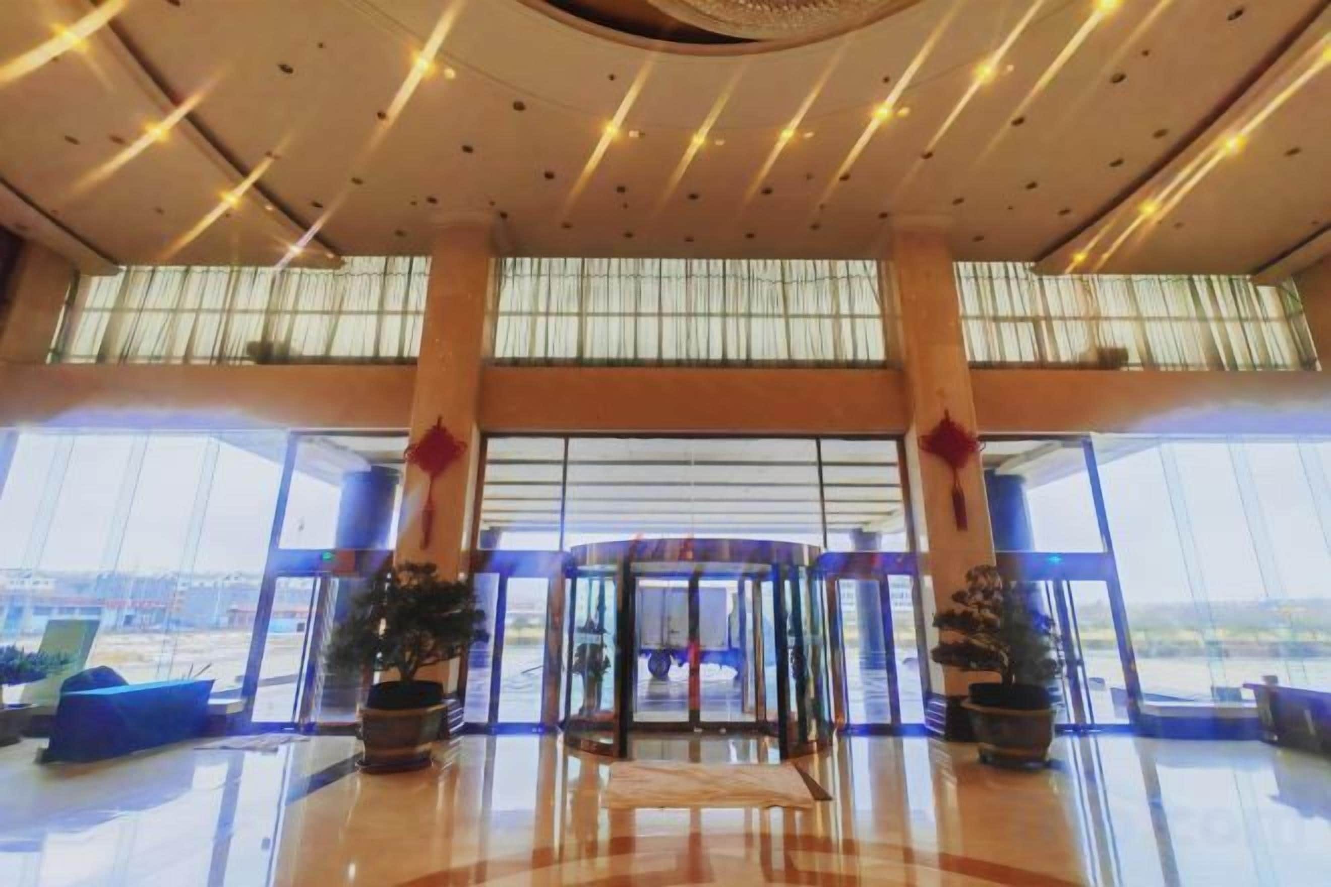 A spacious lobby with a revolving door, large windows, and potted plants.