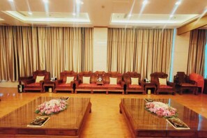 A conference room with a long table, several sofas, and curtains. - Haizheng Hotel (Weifang)