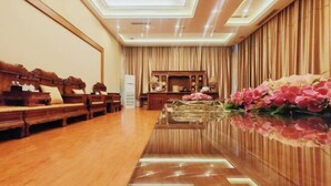 Eine Hotlellobby mit einem Holzerreptionsschreibtisch, einer Sitzecke mit Sofas und einer dekorativen Blumenkomposition.