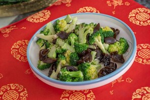 Un tazón con vegetales mezclados sobre una mesa con mantel rojo estampado.