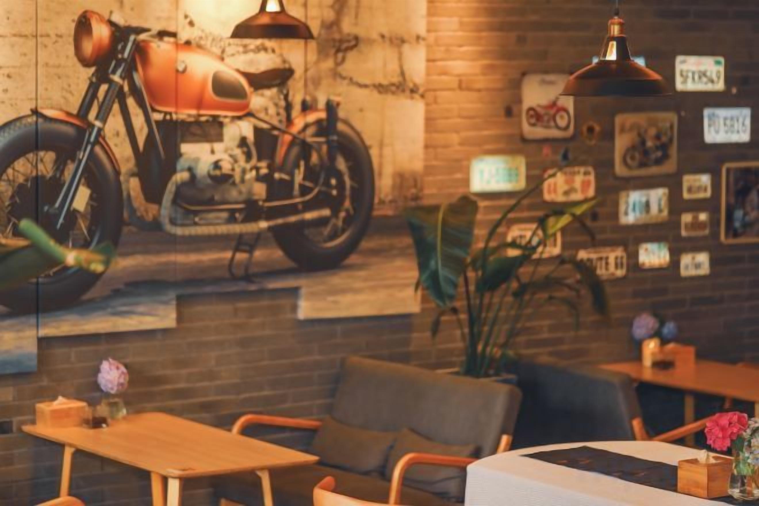 A cozy cafe with a vintage motorcycle mural, comfortable seating, and a rustic brick wall.