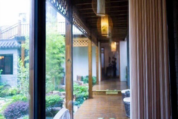 A wooden corridor with a view of a garden and a building outside. - Wuxi Dayin Mountain Residence Garden Homestay (Wuxi)