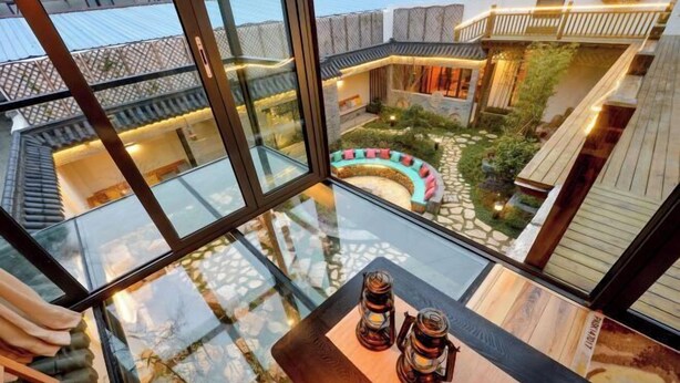 A modern interior with a glass table, two lanterns, and a view of a courtyard with a curved seating area and a stone pathway. - Wuxi Dayin Mountain Residence Garden Homestay (Wuxi)