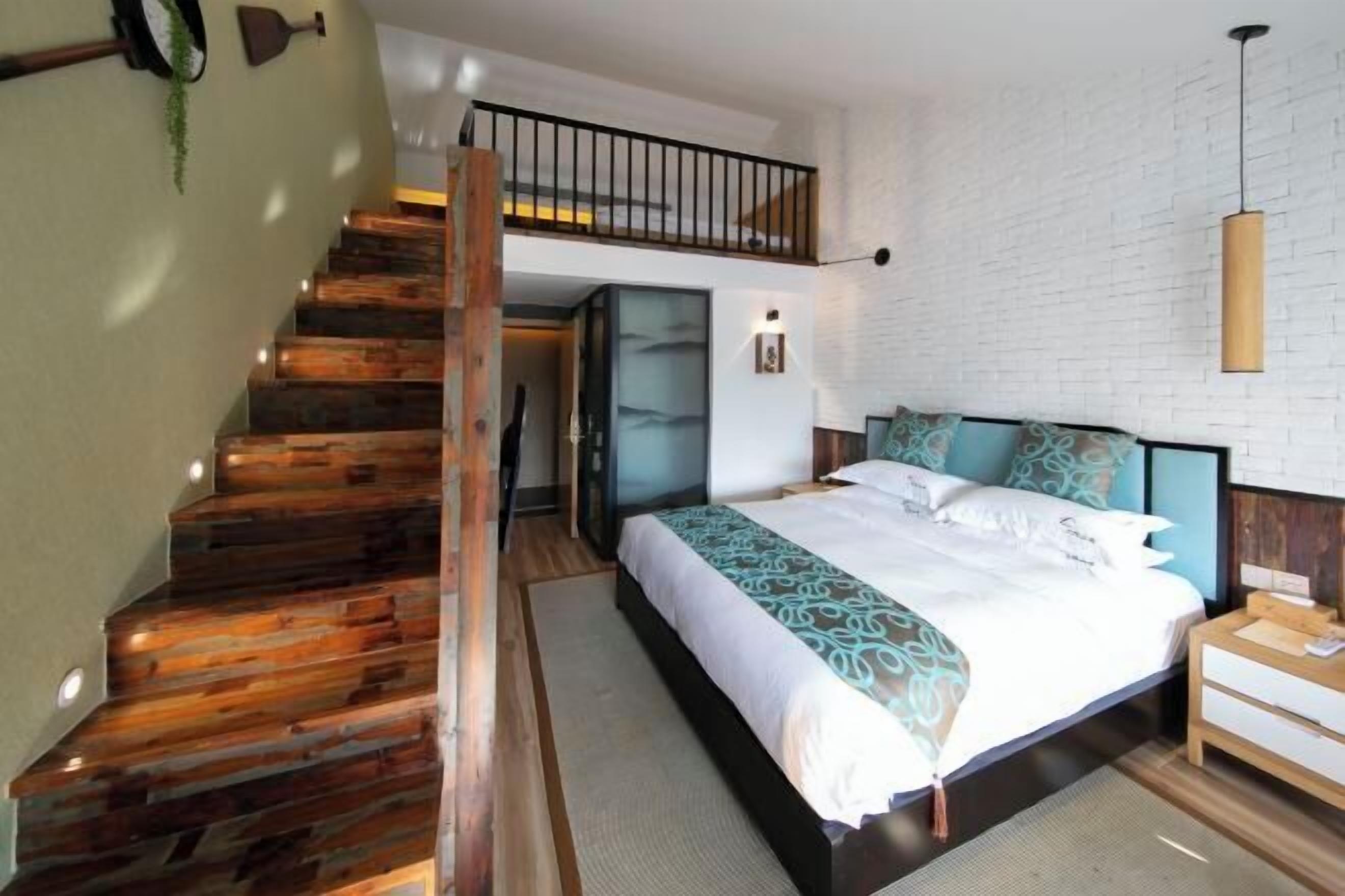 Un dormitorio con escalera de madera, cama con ropa de cama estampada, mesita de noche y lámpara colgante.