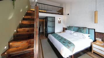 Un dormitorio con escalera de madera, cama con ropa de cama estampada, mesita de noche y lámpara colgante.