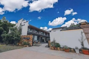 A modern building with a stone entrance, a flat roof, and a clear sky. - Wuxi Dayin Mountain Residence Garden Homestay (Wuxi)