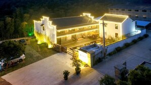 A hotel with a well-lit exterior, a covered outdoor seating area, and a parking lot. - Wuxi Dayin Mountain Residence Garden Homestay (Wuxi)