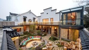 A courtyard with a circular seating area, stone pathway, and a glass structure. - Wuxi Dayin Mountain Residence Garden Homestay (Wuxi)