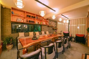 A dining area with a long wooden table, multiple chairs, and a brick wall with shelves. - Wuxi Dayin Mountain Residence Garden Homestay (Wuxi)