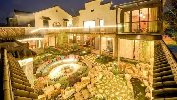 A courtyard with a circular water feature, stone pathways, and a wooden deck. - Wuxi Dayin Mountain Residence Garden Homestay (Wuxi)