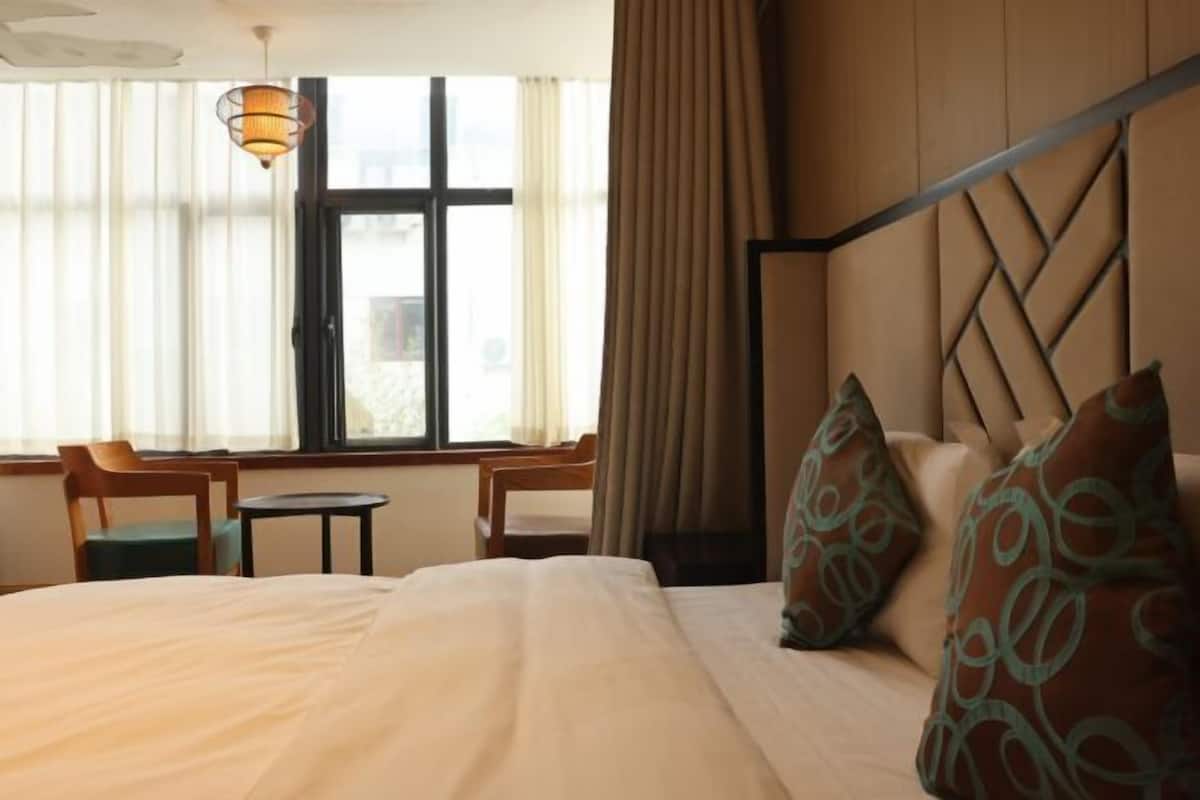 A hotel room with a bed, a desk, and a chair near a window.