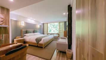 Habitación de hotel moderna con una cama grande, una zona de estar, una bañera de madera y vistas a zonas verdes al exterior.