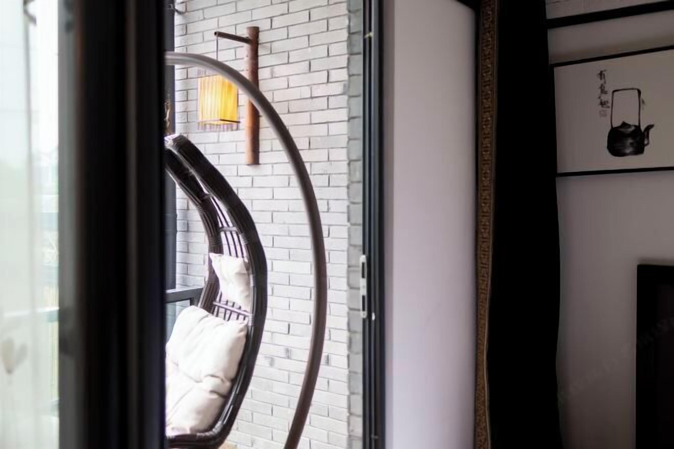 Una habitación con pared de ladrillo blanco, ventana con marco negro y un cuadro con una tetera.