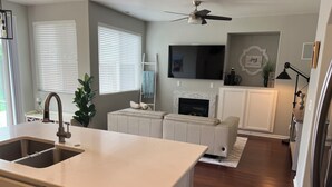 A modern kitchen with a built-in island, a dining area with a white table, and a living room with a fireplace. - 4 Bedroom with all the things! (Eugene)