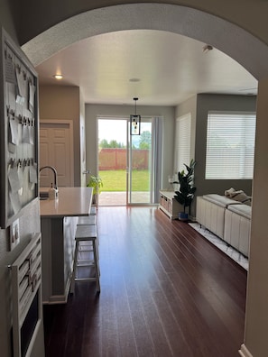 A spacious kitchen with a central island, a dining area with a bench, and a sliding glass door leading to a backyard. - 4 Bedroom with all the things! (Eugene)