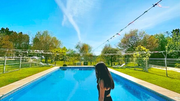 Une piscine, avec un ciel dégagé et des arbres en arrière-plan.
