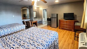A hotel room with two beds, a ceiling fan, a TV, a dresser, and a microwave. - Westerner Motel (Port Allen)
