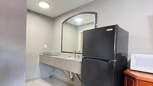 A compact kitchen with a refrigerator, microwave, and sink. - Westerner Motel (Port Allen)