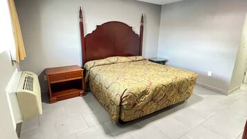 A bedroom with a wooden bed, a bedside table, a small nightstand, and a wall-mounted air conditioner.