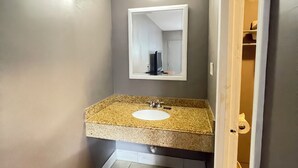 A bathroom with a granite countertop sink, a mirror above it, and a light fixture on the ceiling. - Westerner Motel (Port Allen)