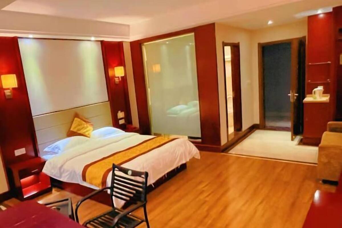 A hotel room with a bed, a chair, a desk, a wardrobe, and a door.