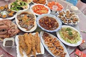 Une table où sont présentés divers plats de fruits de mer, notamment du poisson frit, des crevettes et des beignets d’huîtres.