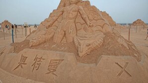 A large sand sculpture of a figure with a detailed head and body, surrounded by smaller sculptures. - Dongdaihe Haizhiyuan Guesthouse (Suizhong)