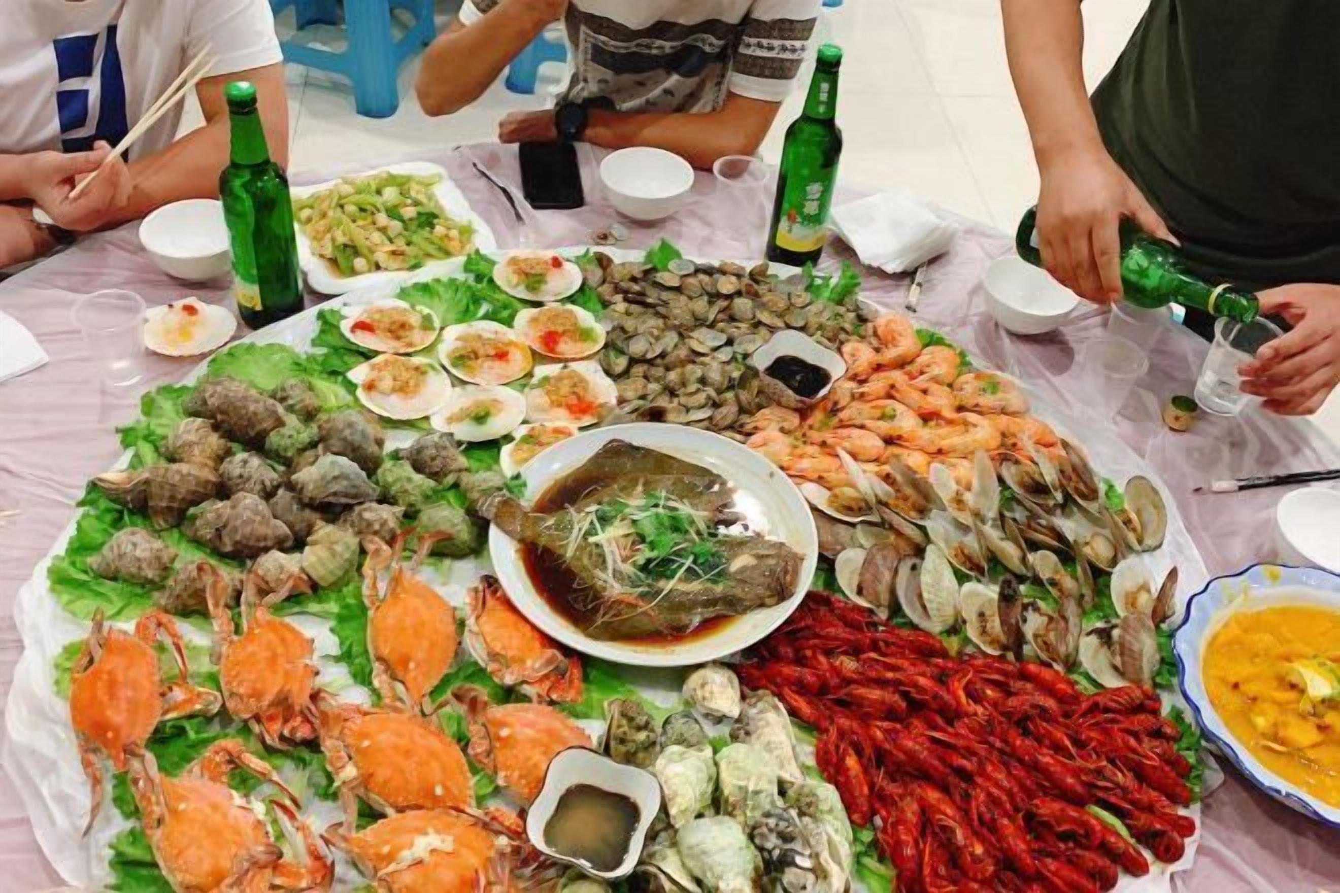 A table with various seafood dishes, including clams, shrimp, and crabs, arranged for a meal.