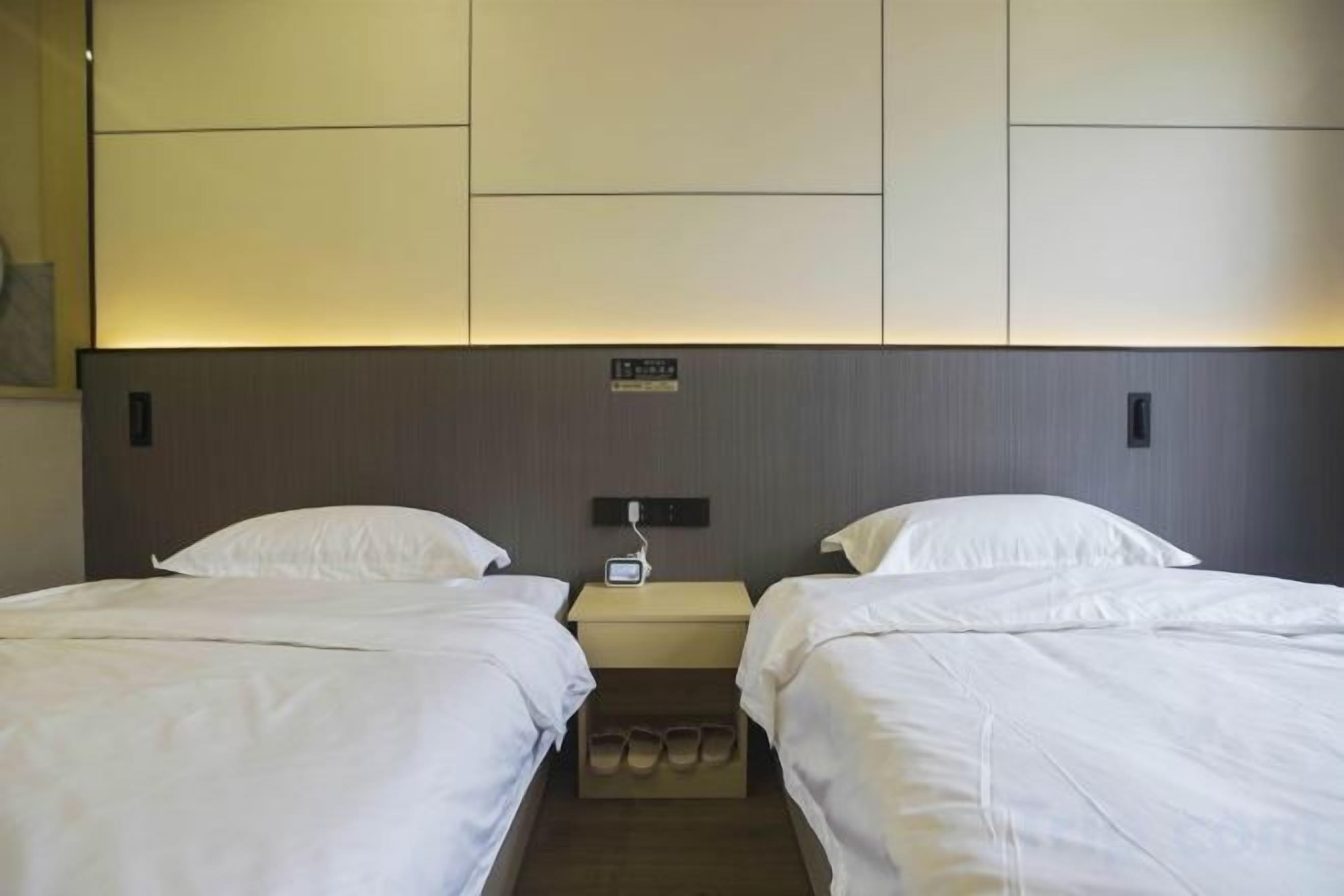 Una habitación de hotel con dos camas, una mesita de noche y un estante empotrado.