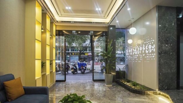 Un hall de hotel con una recepción, un área de descanso y vistas a la calle.