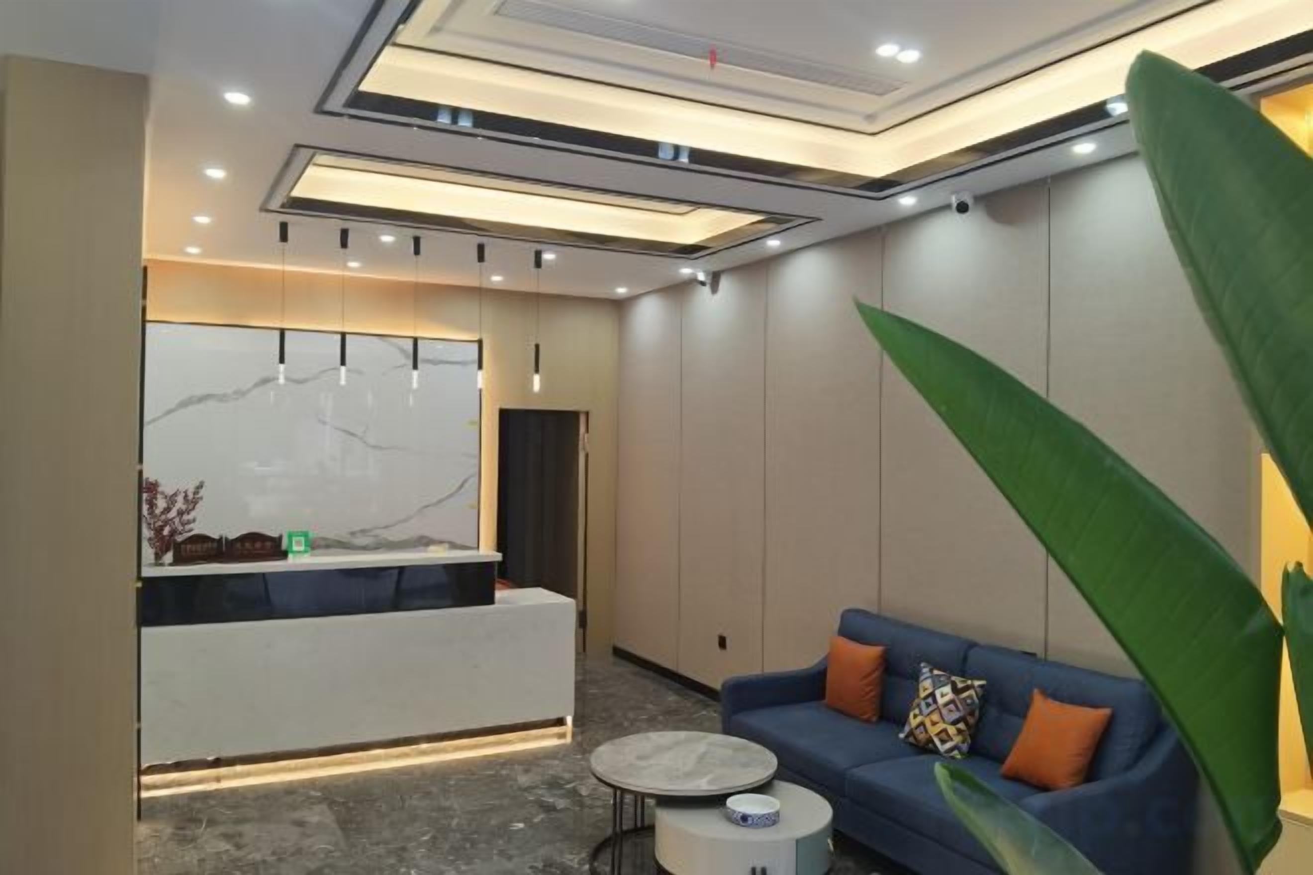 A modern reception area with a marble counter, a blue sofa with orange cushions, and a round coffee table.