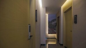 Un pasillo con puertas, un zócalo iluminado y una vista de un edificio en la distancia.