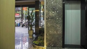 Un vestíbulo moderno con pared de mármol, un ascensor y una planta en maceta.