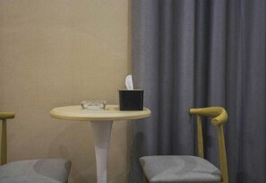 A small round table with a tissue box and glass, a grey cushioned chair, and a wooden chair with a curved backrest. - Wuyuan Jindan City Homestay (Wuyuan)