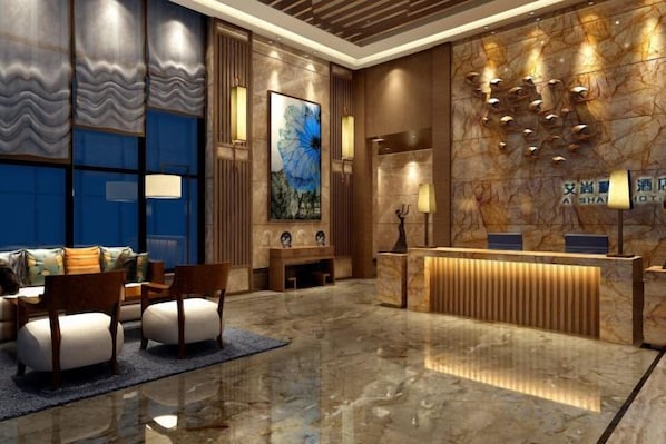 A hotel lobby with a reception desk, seating area, and a large abstract painting.